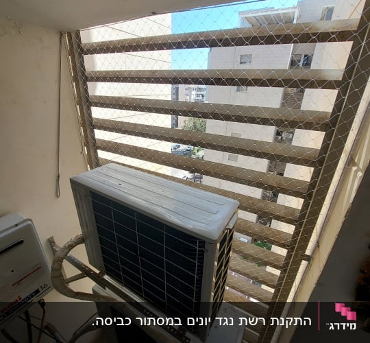 רשת מתכת על חלון עם מזגן חיצוני